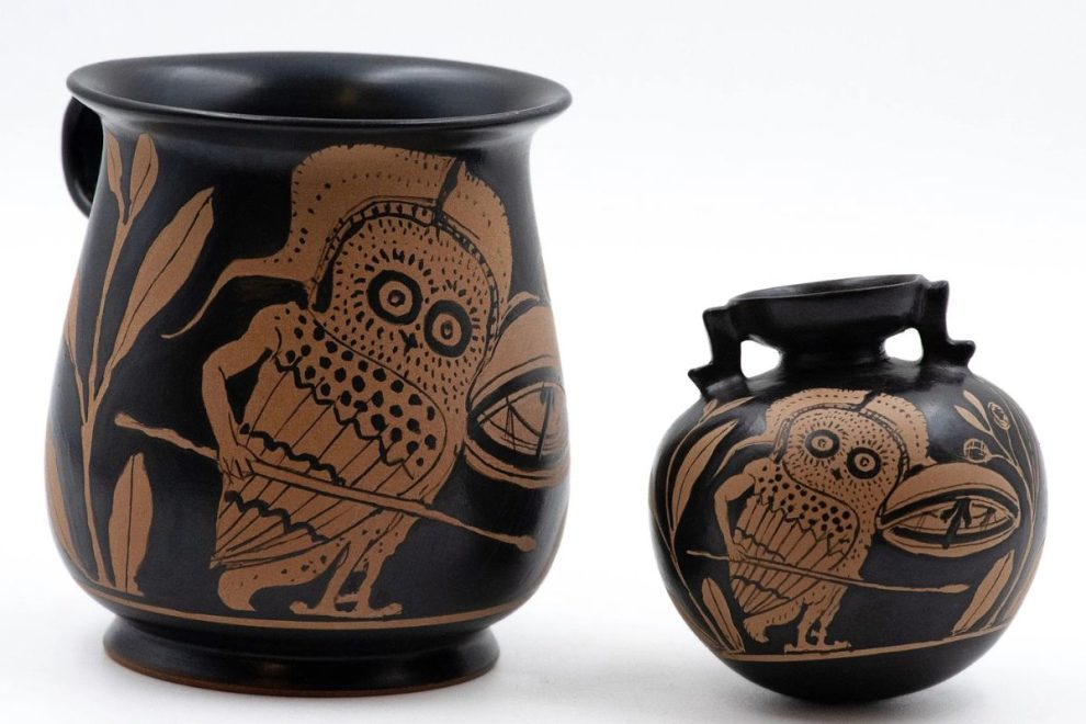 Two black ceramic vessels featuring a stylized owl motif, placed against a light background.