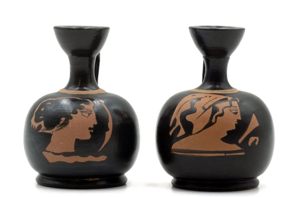 Two black pottery vessels featuring terracotta female profiles, positioned side by side.