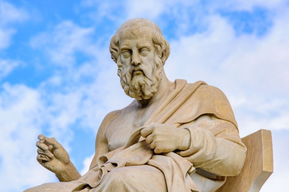 A marble statue of the ancient Greek philosopher Plato against a backdrop of a blue sky with scattered clouds.