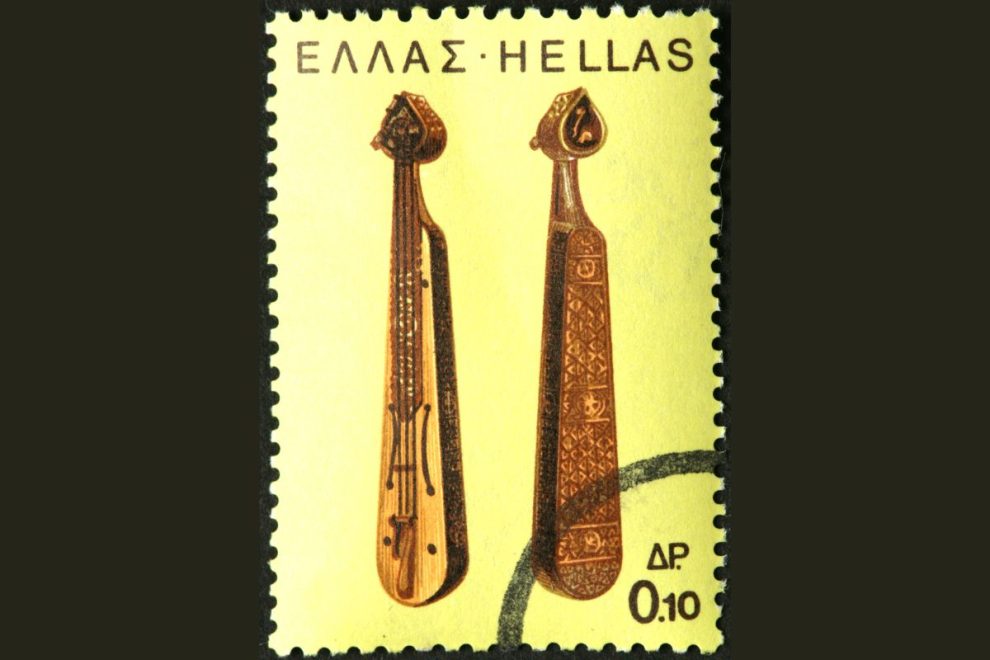 A Greek postage stamp featuring two traditional stringed musical instruments against a yellow background, highlighting their intricate craftsmanship.