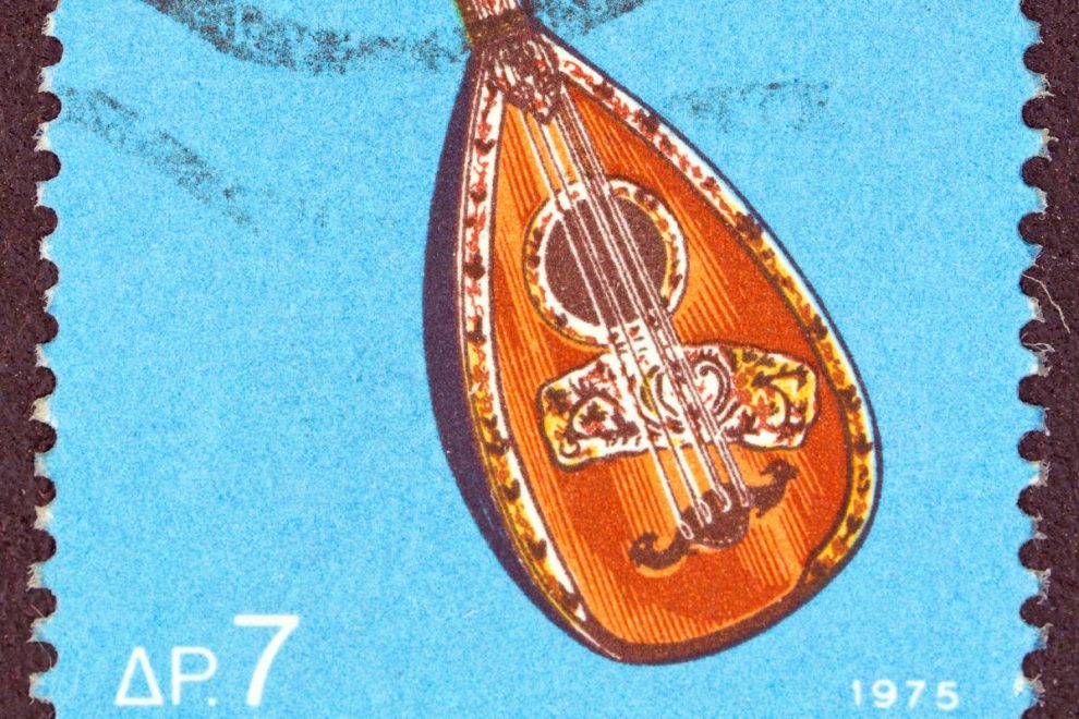 A vintage postage stamp featuring a Greek laouto, a traditional stringed musical instrument, against a blue background.