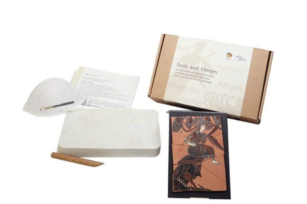 Athena - Gods & Heroes Archaeology Digging Kit, featuring a boxed set with tools, a plaster block, a protective mask, and pottery shards depicting a Greek mythological scene. The kit is designed for an interactive excavation experience_old greek pottery