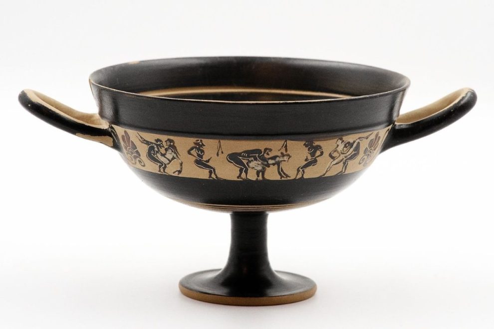 A Kylix, an ancient Greek drinking cup with two handles, featuring a band of miniature erotic scenes in black-figure decoration.