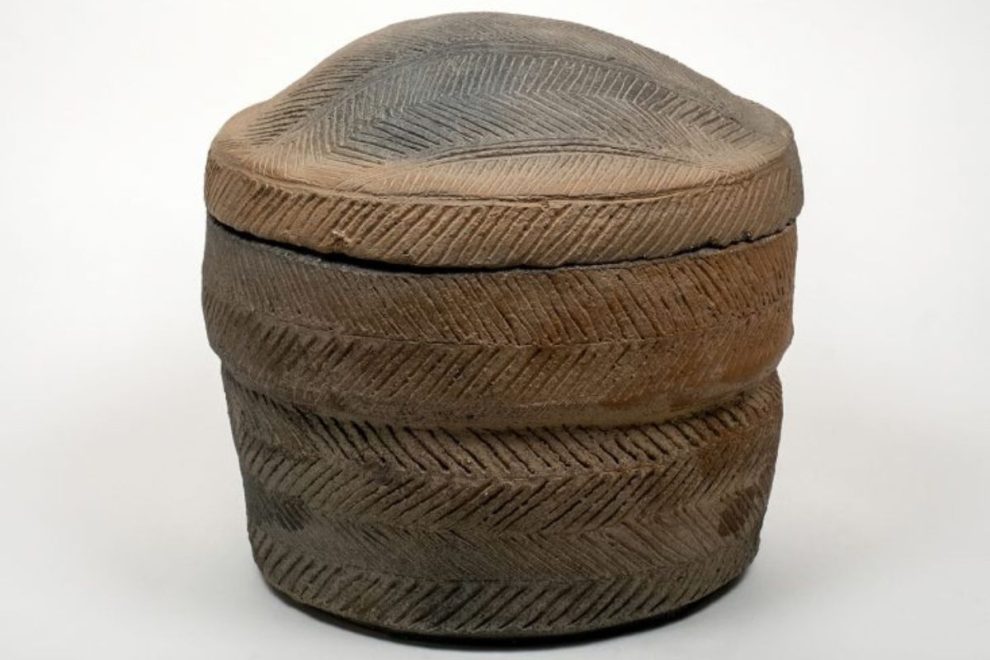 A ceramic pyxis box with a lid, featuring a textured, patterned surface.